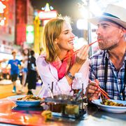 Middle-aged man and his companion handsome blond lady on a tuk-tuk ride in Bangkok