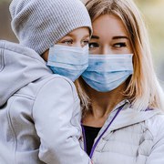 a girl with a child stands on the road in a protective medical mask. Dense smog on the streets. Epidemic of the flu