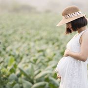 Pregnant woman touching her big belly and walking in the park