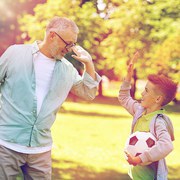 family, generation, gesture, sport and people concept - happy grandfather and grandson with football ball making high five at at summer park