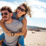 Boyfriend carrying his girlfriend piggyback on the beach